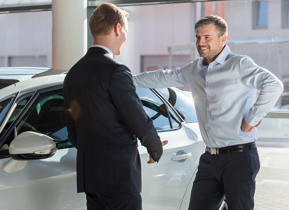 Workers’ Compensation Insurance for Auto Dealerships in Maryland - Two Business Colleagues Talking Next to a Showroom Car